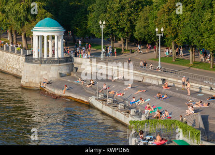 Unidentified people sunbathing at the Gorky Park at Moskva River bank on a sunny day. Moscow, Russia. Stock Photo