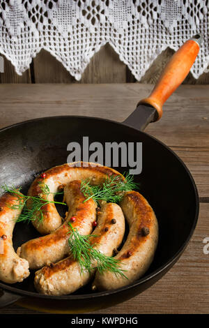 Grilled sausages on a wooden background, knitted decorations in the background Stock Photo