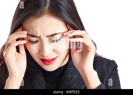 studio shot of a young asian business woman having a headache, painful and miserable, hand on temple, isolated on white background. Stock Photo