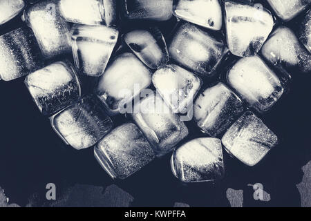 Texture of ice cubes on a dark background. Chaotic scattered icicles on a black background. Winter background. New Year pattern. Stock Photo