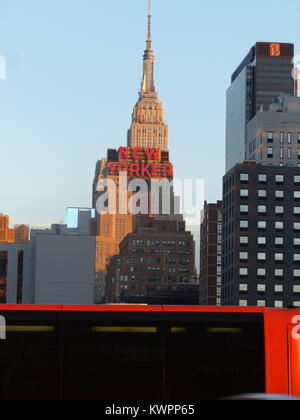 New York City's Empire State Building with red 'New Yorker' sign for Hotel New Yorker. and red Bolt buses. The 443 meters tall Empire State Building w Stock Photo