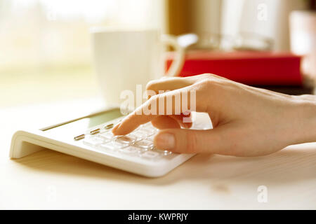 Financial data analyzing hand writing and counting on calculator at home on wooden desk Stock Photo