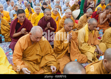 Monks praying at the foot of the Bodhi tree (where the Buddha is said to have gained enlightenment) at the Mahabodhi Temple in Bodhgaya, India Stock Photo