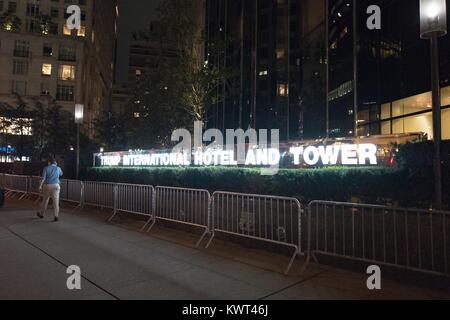 A man walks past barricades at night outside the Trump International Hotel and Tower on Columbus Circle in Manhattan, New York City, New York at night, with illuminated sign visible, September 14, 2017. () Stock Photo