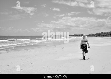 Women walking alone on a remote tropical beach, Balgal Beach, Queensland, Australia Stock Photo