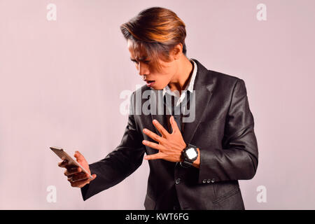 Indian man looking at mobile with a shocked expression, Pune, Maharashtra Stock Photo