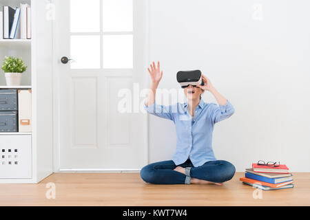 young beauty female teacher wearing VR technology device looking education information and using hands to organize school teaching class content. Stock Photo