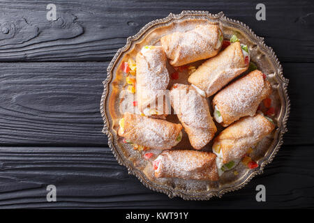 Sicilian cannoli stuffed with ricotta and candied fruits close-up on a plate on a table. horizontal top view from above Stock Photo