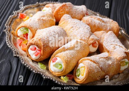 Sicilian cannoli stuffed with ricotta and candied fruits close-up on a plate on a table. horizontal Stock Photo