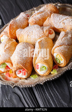 Delicious sweet rolls cannoli with cheese cream and candied fruit close-up on a plate. vertical Stock Photo