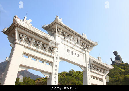 Entrance gate to Tian Tin monastery and the Big Buddha on the mountain behind at Ngong Ping village on Lantau Island, Hong Kong, China. Stock Photo