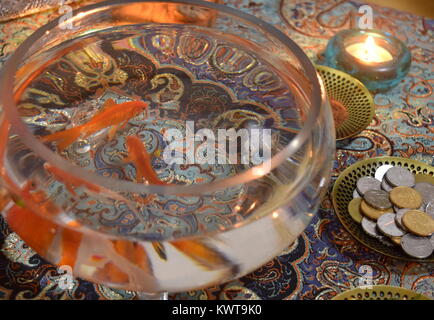 Fishbowl with goldfish on top of a termeh handwoven Iranian textile part of haft-seen tabletop, a traditional arrangement for the Iranian New Year Stock Photo