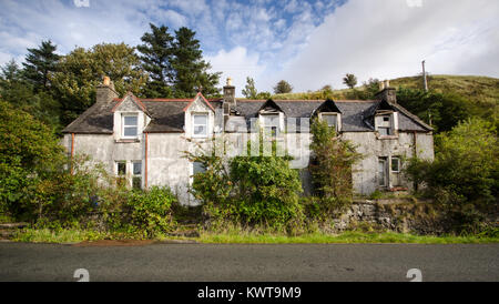 A partially derelict and damaged house is overgrown with shrubs in the remote village of Uig on the Isle of Skye in the Highlands of Scotland. Stock Photo