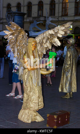 Lvov, Ukraine - 24.08.2016: Golden live angel statue in evening street. Girl in form of angel in city Stock Photo