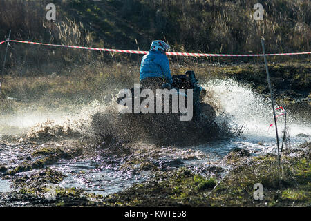 Lviv,Ukraine- December 6, 2015:  Unknown rider on ATV overcomes a water barrier near Lviv, Ukraine Stock Photo