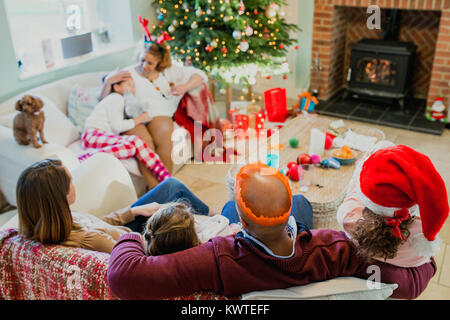 Tired family relacing together in the living room of their home at christmas time. Stock Photo