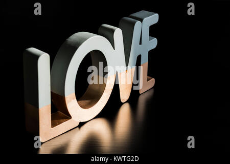 Two-toned "Love" Reflecting on Black Wooden Table Stock Photo