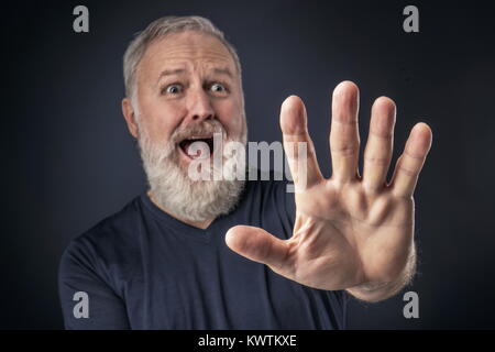 Old man in shirt and scared with his stretched hand forward Stock Photo