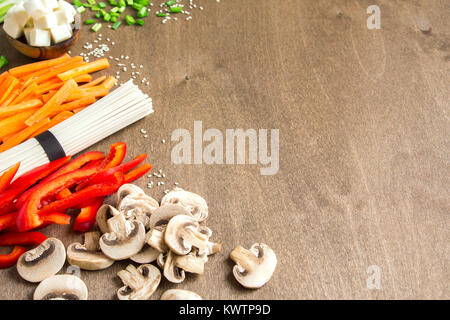 Vegetarian vegan asian food ingredients for stir fry with tofu, noodles, mushrooms and vegetables over wooden background with copy space. Stock Photo