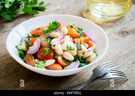 White Bean Salad with Cherry Tomatoes, Onion and Parsley on wooden background, copy space - healthy homemade organic vegetarian vegan diet protein sal Stock Photo