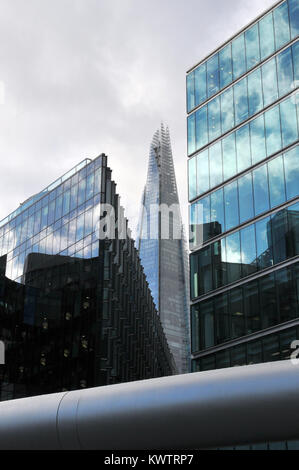A different or unusual view of the shard from an alternative angle between two office buildings made from glass in central London. Stormy skies cloudy Stock Photo