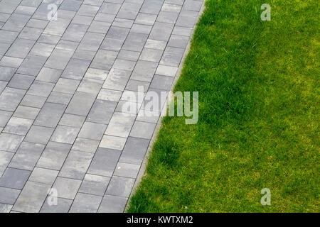 Grey tiles and green grass outdoors Stock Photo