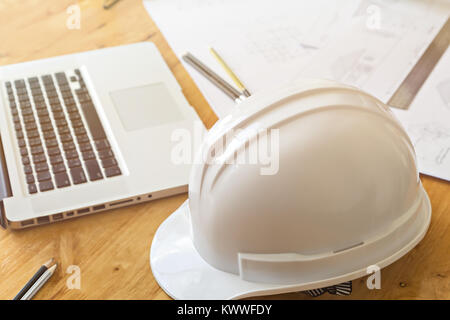 Close up of helmet  with architect sketching a construction project and laptop Stock Photo