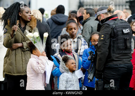 London, UK. Black family talking to a female armed police officer outside St Paul's Cathedral after a memorial service (14th Dec 2017) for the Grenfel Stock Photo