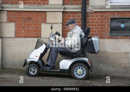 Elderly man sitting on a mobility scooter outside a bank Stock Photo