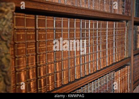 An antique and historical library containing many old leather-bound books from the 18th and 19th centuries, tightly stacked on shelves. Stock Photo