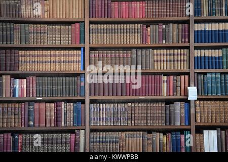 An antique and historical library containing many old leather-bound books from the 18th and 19th centuries, tightly stacked on shelves. Stock Photo