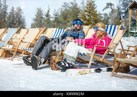 Skiers couple in sun lounger relax and enjoy on sun Stock Photo