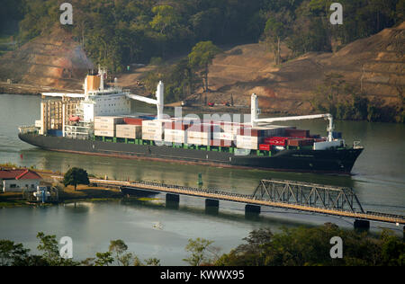 Container vessel passing through the Panama Canal, Republic of Panama. In the foreground is the car and railroad brigde over Rio Chagres at Gamboa. Stock Photo