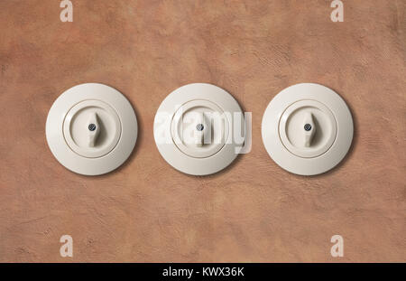 Three switches vintage round with button from porcelain isolated on light brown stucco wall. Close up, detail. Stock Photo