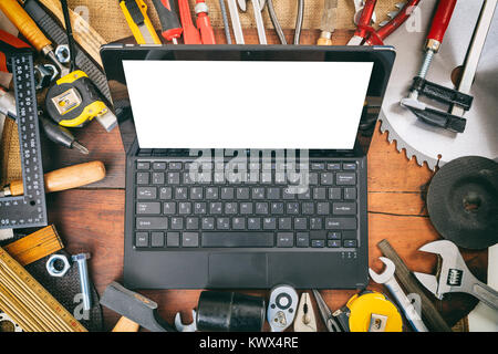 Variety of hand tools and laptop on a wooden table Stock Photo