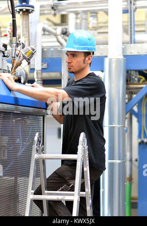 operator repairs a machine in an industrial plant with tools Stock Photo