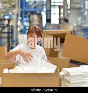 woman works in the shipping department of a company and packs styrofoam components into packages for the customer. Stock Photo