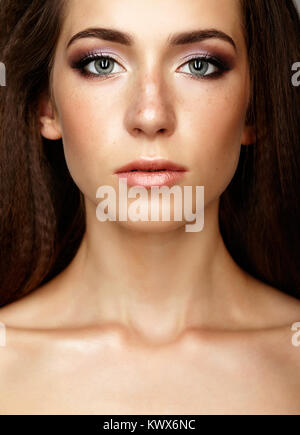 Closeup beauty portrait of young woman. Brunette girl with long hair and day female makeup. Stock Photo