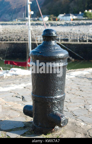 An old cannon buried in the side of a dock, recycled and now used as a mooring point for boats. Stock Photo