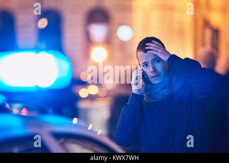 Young man calling after a crisis situation on city street. Themes crime, emergency medical service, fear or help. Stock Photo