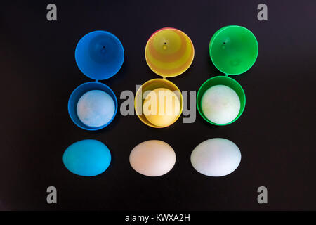 Easter eggs are filled  and viewed from above.  The plastic eggs are filled with dyed eggs and placed in a pattern on the table. Stock Photo