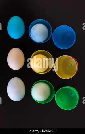Easter eggs are filled  and viewed from above.  The plastic eggs are filled with dyed eggs and placed in a pattern on the table. Stock Photo