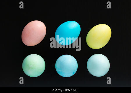 Six Easter eggs are place on a black surface. 3 standing and 3 laying down creating a design. Stock Photo