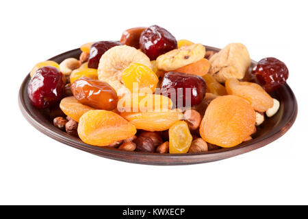 Dried fruits isolated on a white background. Dates, lemon, apricots, figs and nuts in a clay plate. Stock Photo