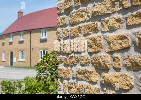 a tradtional stone wall with house in the background Stock Photo