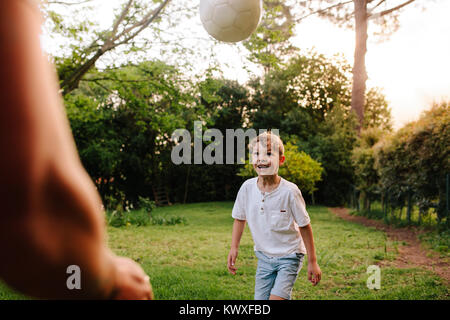 Cute little boy playing football with his father. Father and son in backyard playing with a ball. Stock Photo