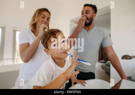 Little boy brushing teeth with his parents in bathroom. Family brushing teeth together in bathroom. Stock Photo