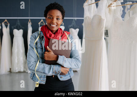 Portrait of wedding dress store owner with a diary. Woman dressmaker in her bridal boutique. Stock Photo