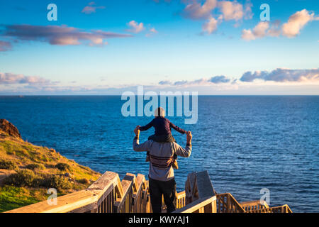 Father giving his son piggyback ride at Hallett Cove boardwalk while enjoying sunset, South Australia Stock Photo