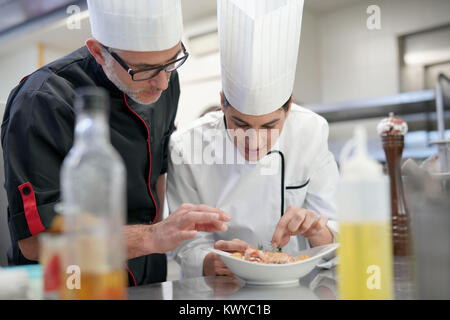 Professional cook chefs in kitchen improving dish composition Stock Photo